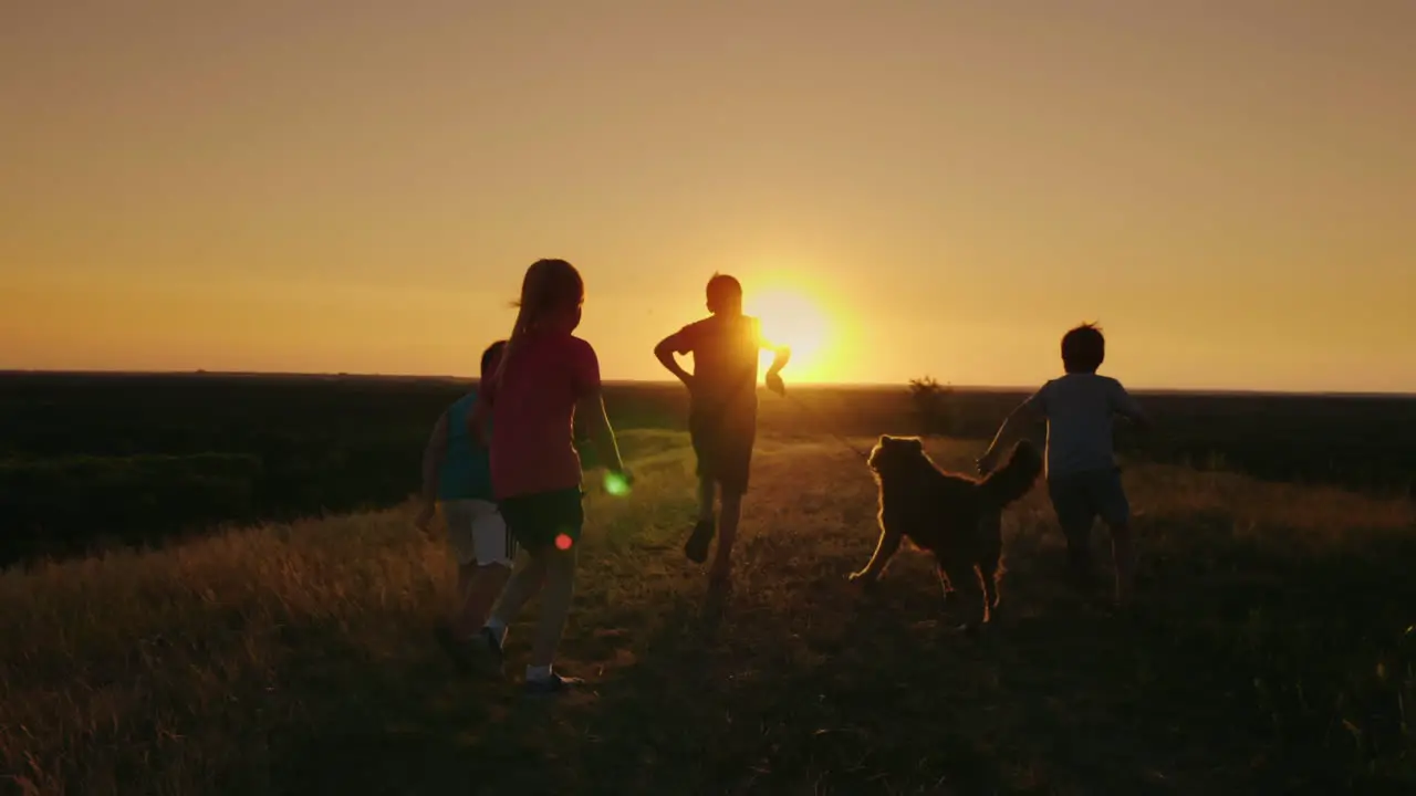 A Group Of Children Are Running Happily Towards The Sunset With The Dog