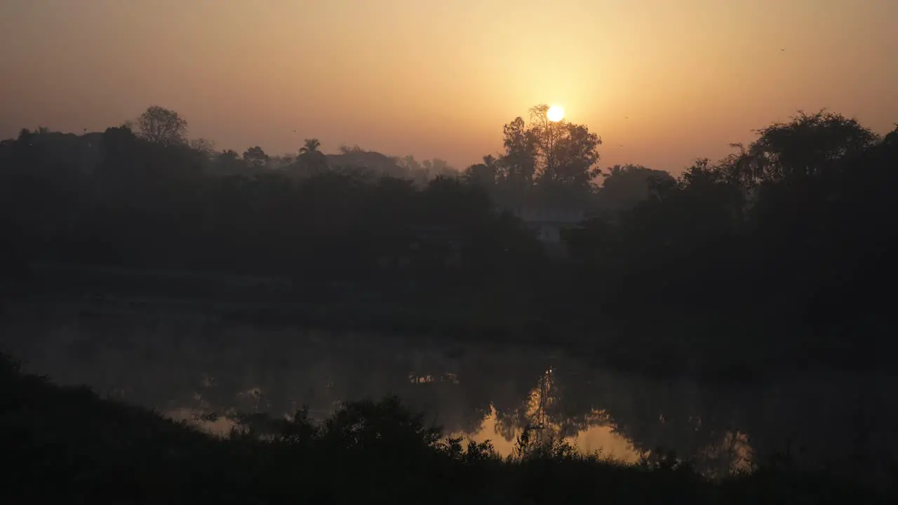 sun rise behind tree near the hot water spring river fog on water mist in air cold morning moving