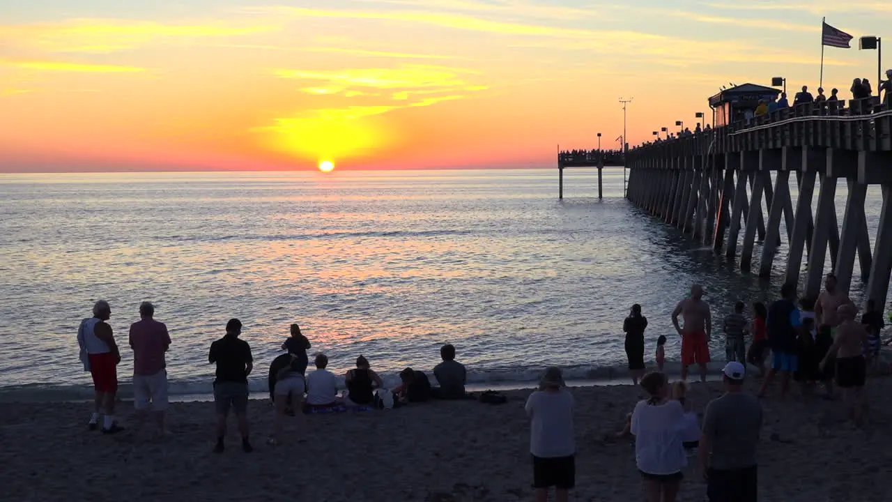 Crowds gather around a pier at sunset in Florida