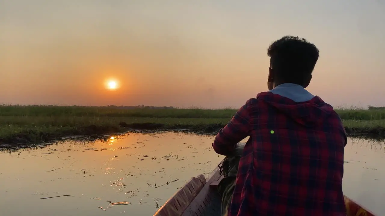 Silhoutte of a man sitting on bow of boat watching sunrise peacefully slow motion