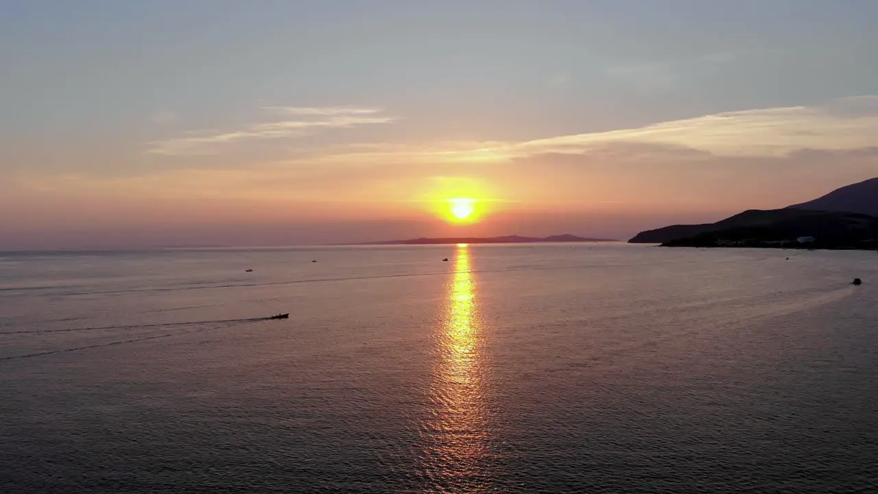 Aerial flight while a boat is approaching to sunlights from left to right on the sea Turkey