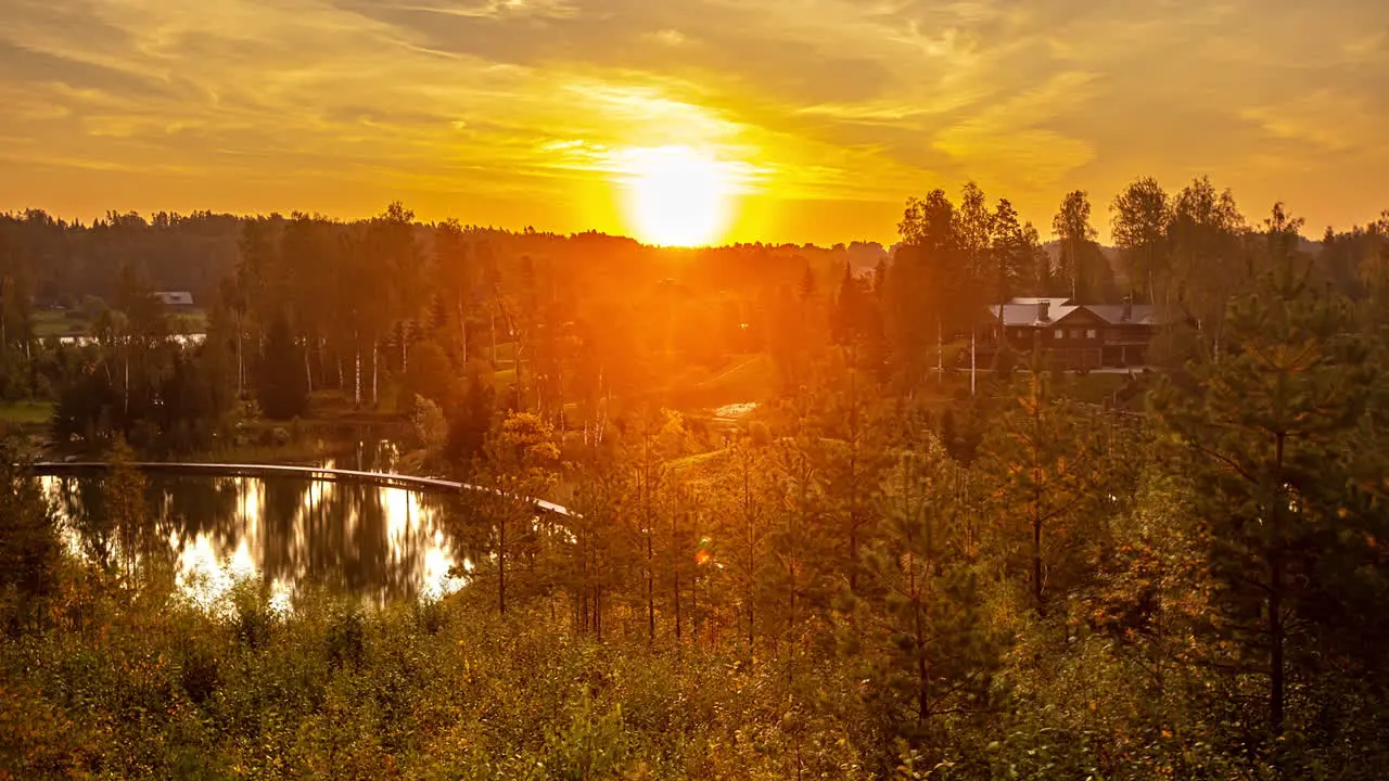 Beautiful time lapse shot of golden morning sunrise at natural lake surrounded by forestry in nature Bright sunbeam shining at cloudy sky 5K Wildlife shot