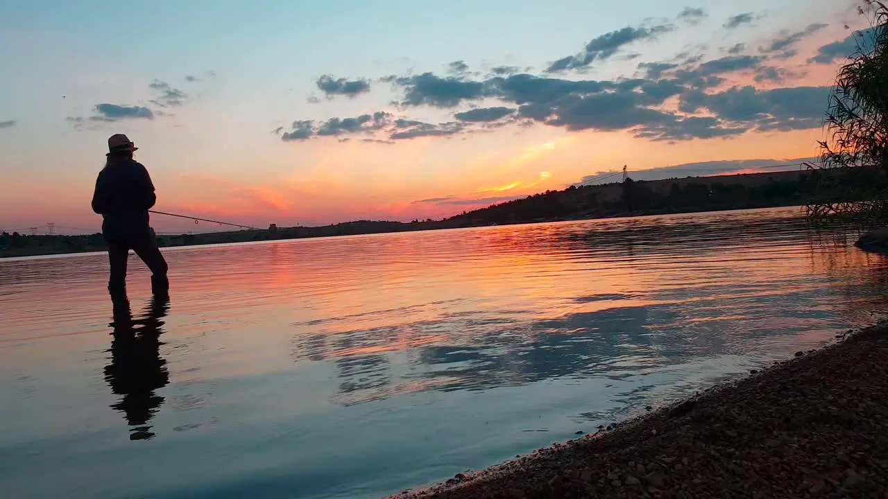 A girl fishing for bass after sunset in a beautiful calm lake