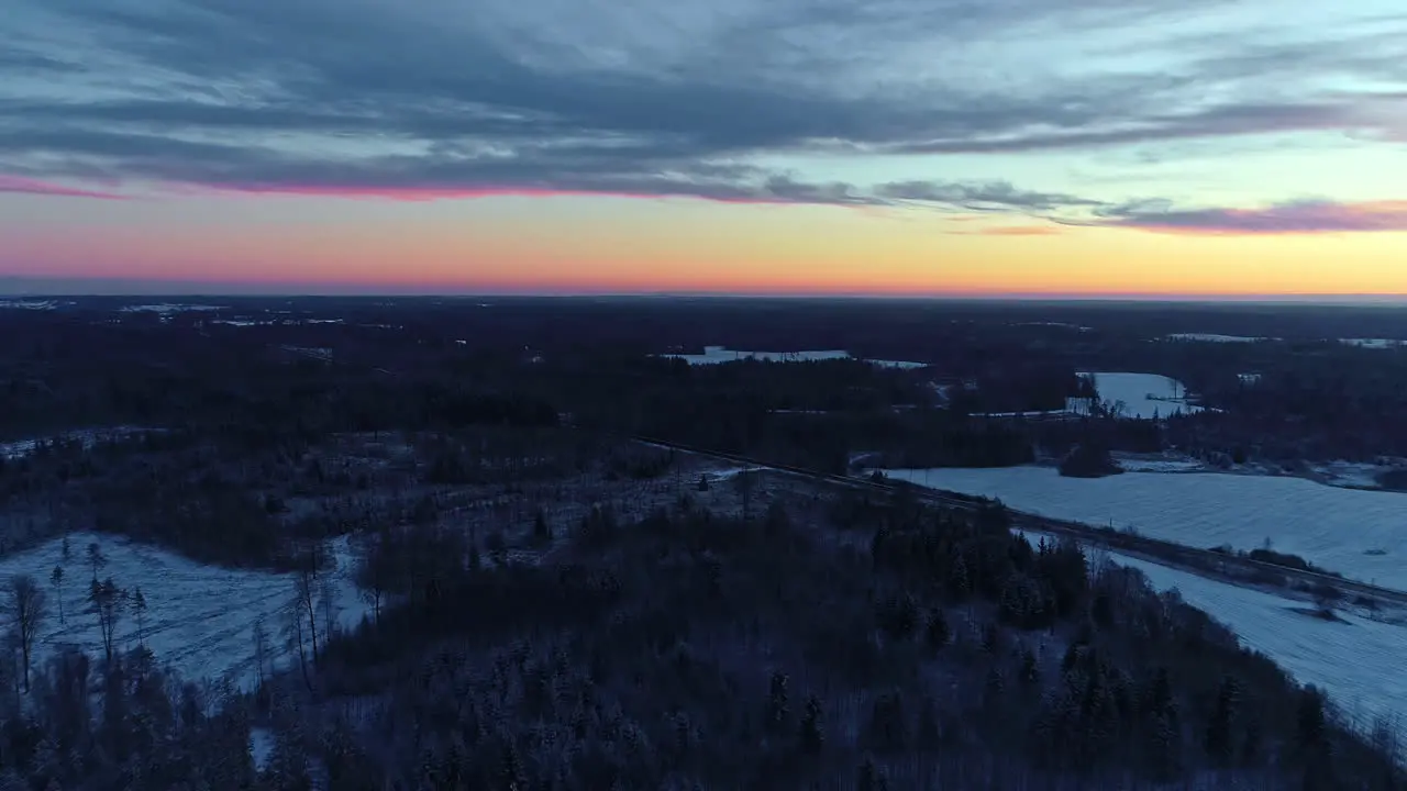 Cold winter woodlands and bright colorful sunset sky aerial view