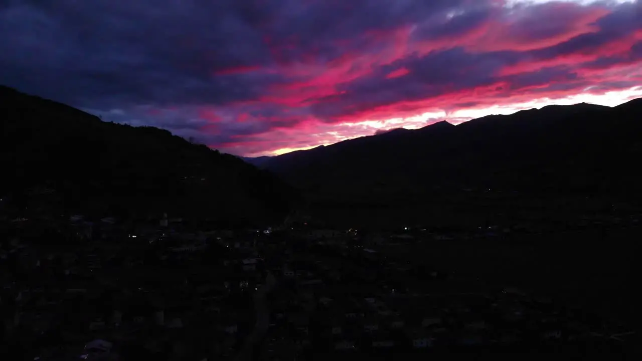 Aerial Sunset View Over Kaprun In Austria With Silhouetted Mountains Against Dramatic Purple Pink Clouds