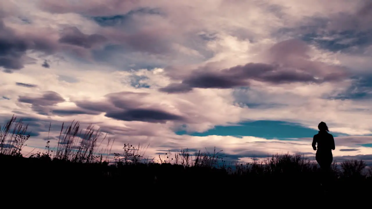 Beautiful black silhouette outline of a female jogger jogging against a dramatic sky