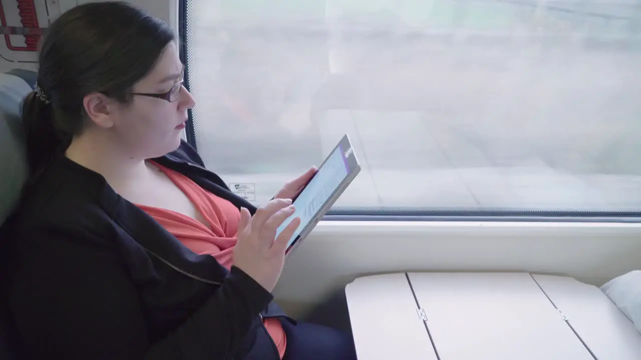 Side View Young professional woman uses touchscreen tablet on train