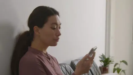 Female Candidate Wearing Suit In Office Waiting For Job Interview Looking At Mobile Phone 2