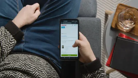 Overhead Shot Of Person At Home Shopping Online Looking At Costco Website On Mobile Phone 2