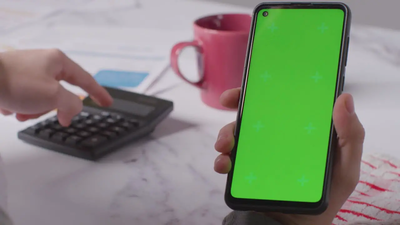 Close Up Of Person Holding Green Screen Mobile Phone Looking Through Bills In Kitchen