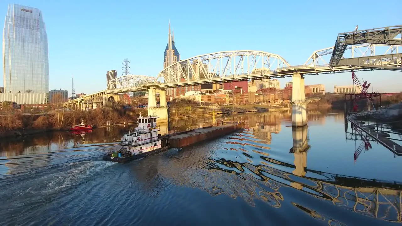 4k aerial nashville tennessee skyline tug boat going under bridge city urban roads