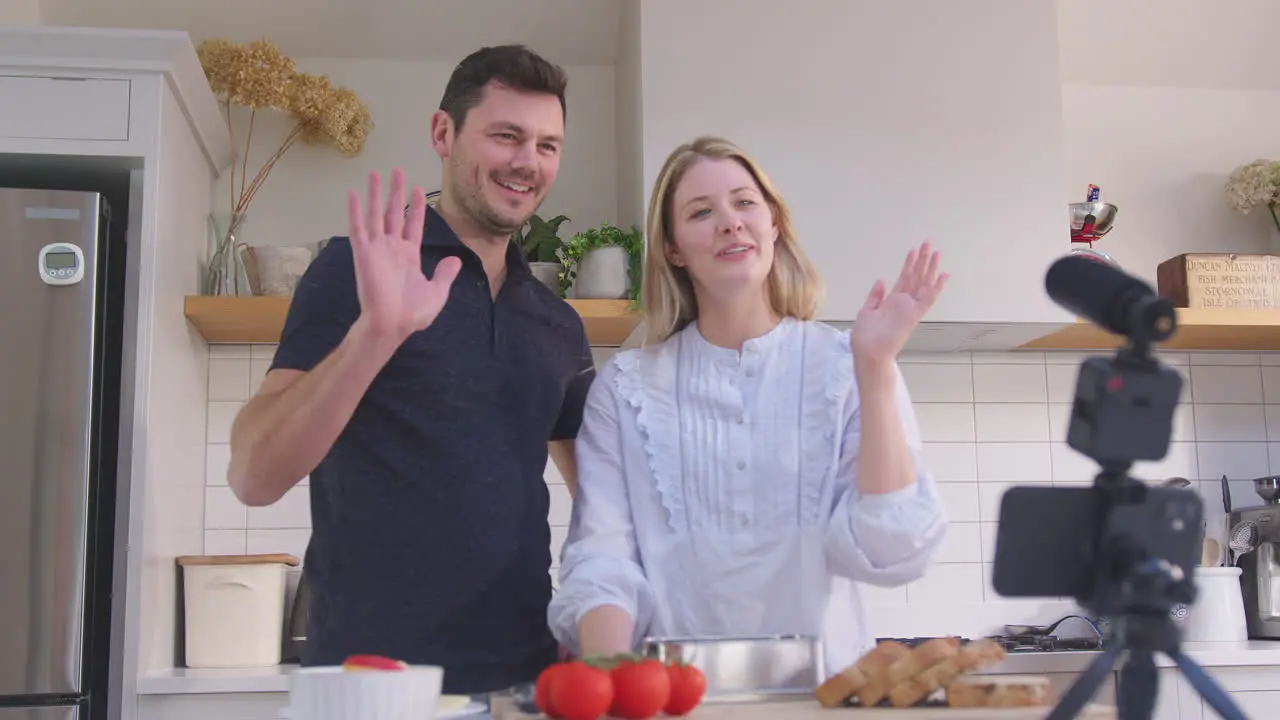 Couple vlogging making social media video about food at home in kitchen on mobile phone shot in slow motion