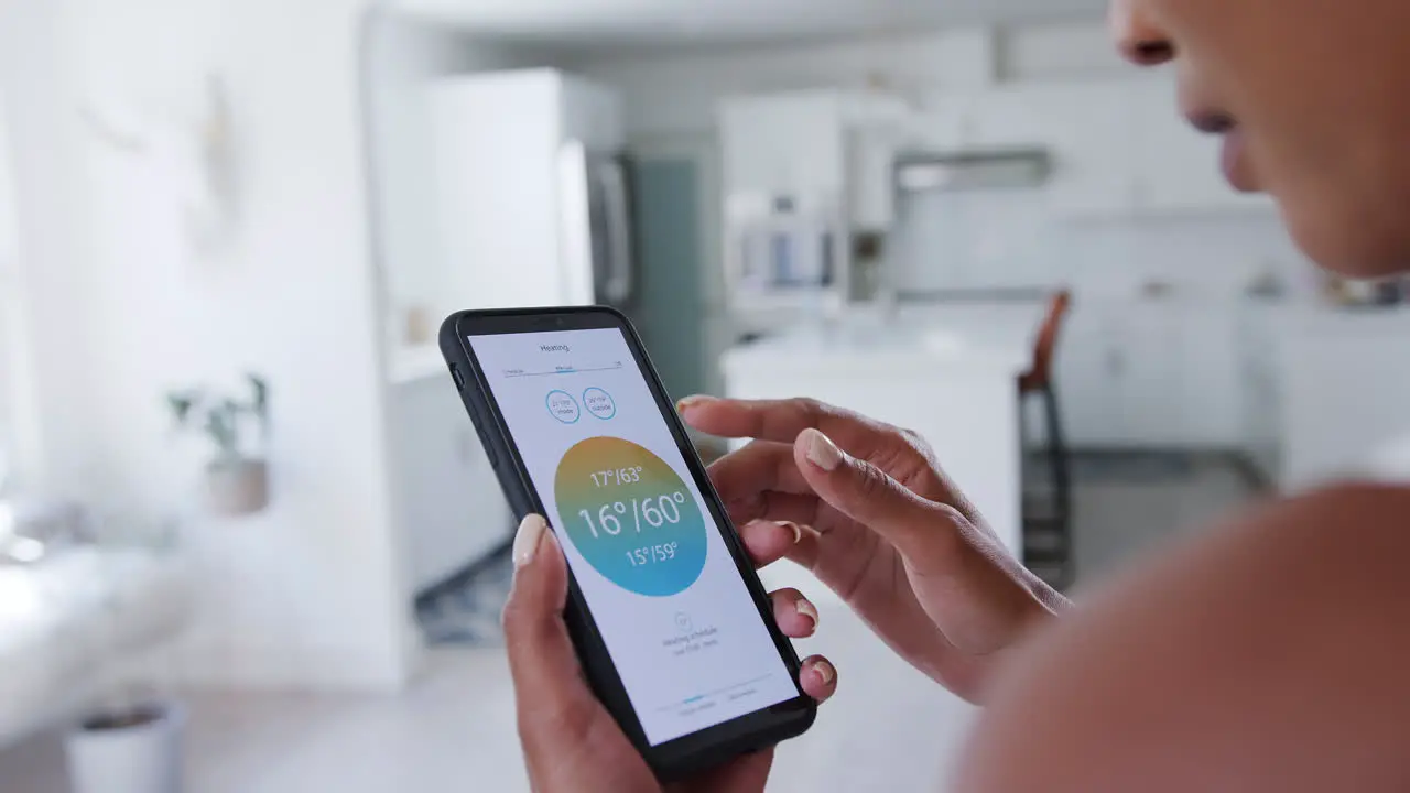 Woman Controlling House Central Heating Temperature Using App On Mobile Phone