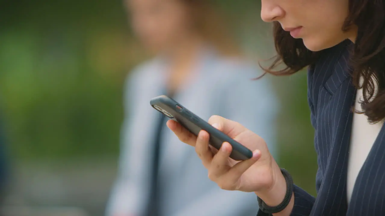 Close Up Of Female Office Workers Outdoors Working On Laptop And Using Mobile Phone During Break