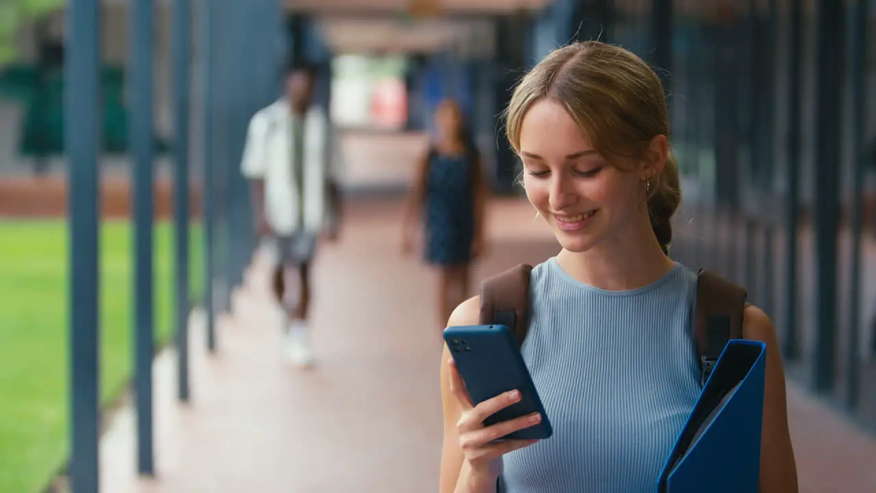 Female High School Or Secondary Student Looking At Social Media Or Internet On Phone Outdoors