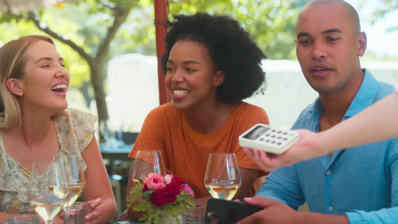 Man Paying Bill At Outdoor Bar Or Restaurant Using Contactless App On Mobile Phone