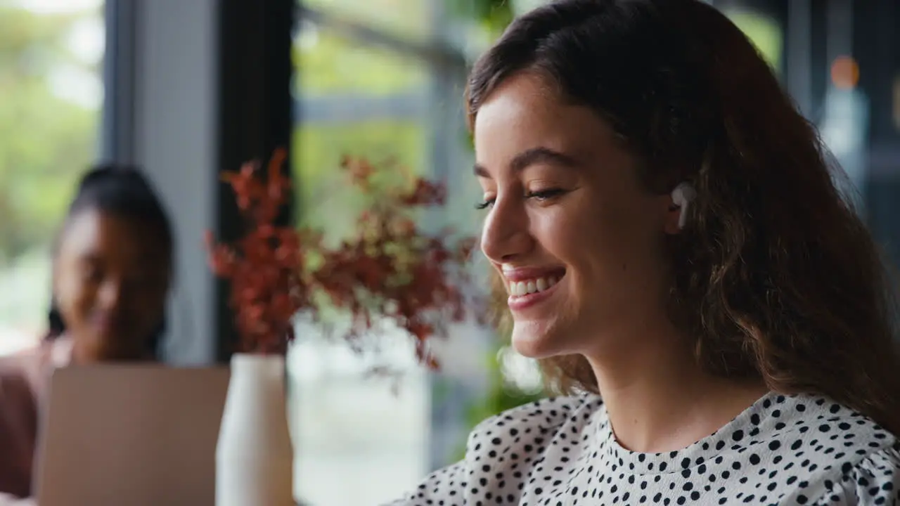 Businesswoman Wireless Streaming Music Wearing Earbuds Working In Coffee Shop