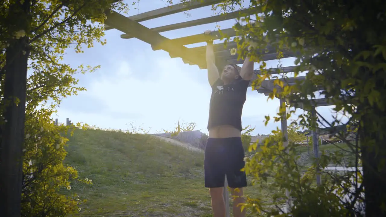 Slowmotion shot of a muscular athlete doing pull-ups in an archway