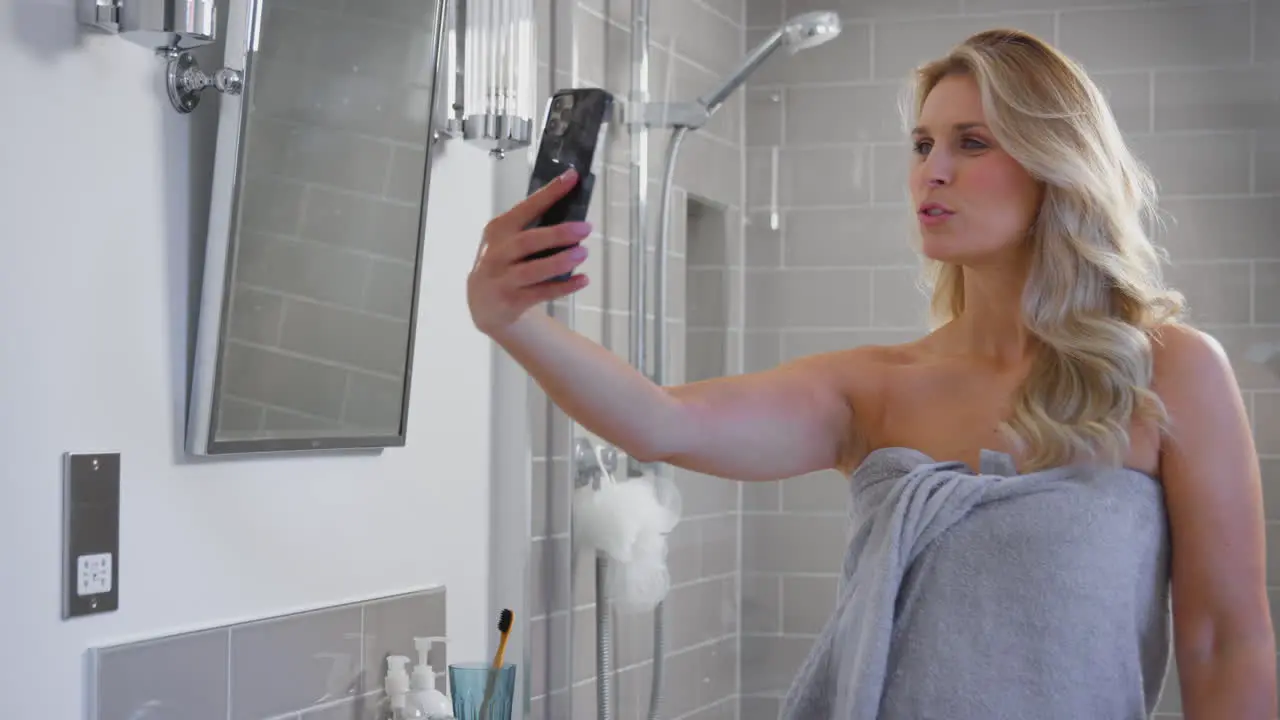 Mature Woman Getting Ready In Bathroom At Home Posing For Selfie On Mobile Phone