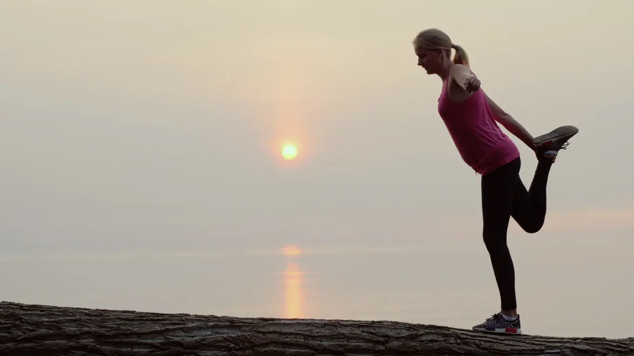 Active Middle-Aged Woman Doing Stretching And Balance Exercise In A Picturesque Place By The Sea