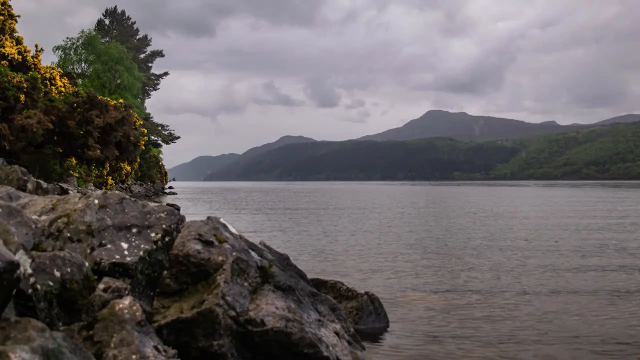 Cinematic timelapse of scottish highland lake with clouds and misty mountains in background