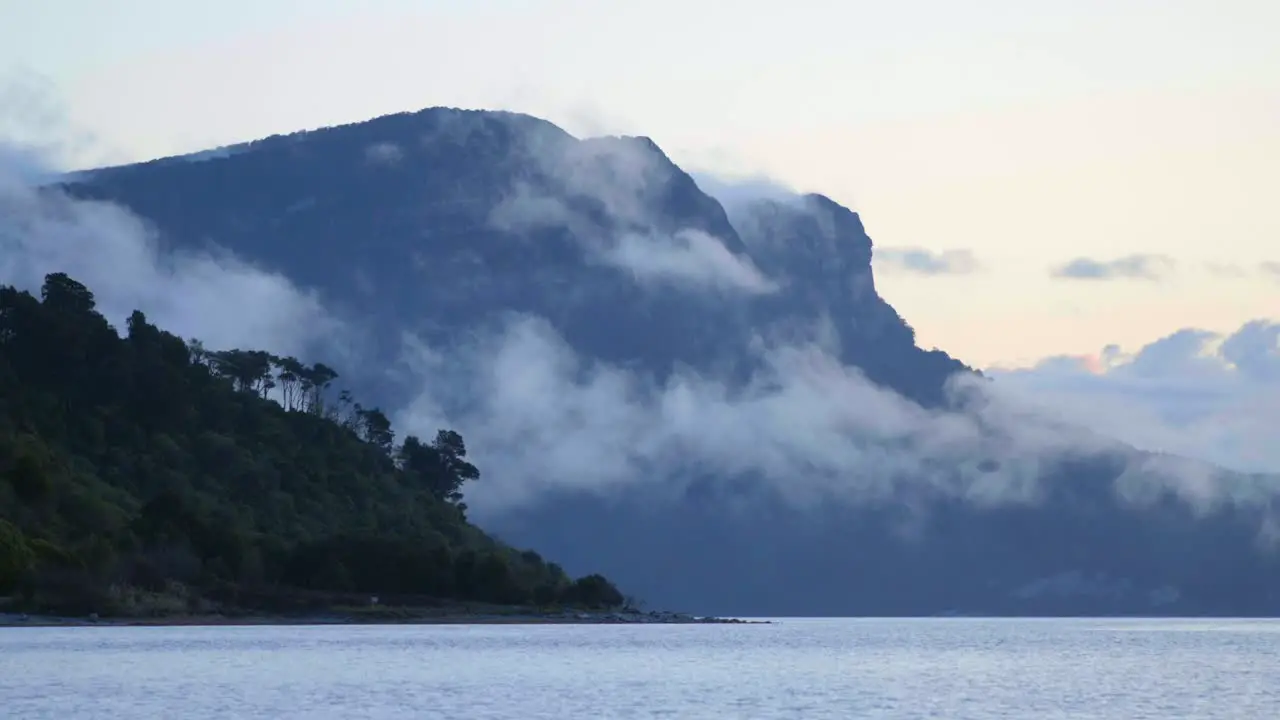 A mesmerizing view of clouds gracefully drifting beneath a towering mountain revealing the dynamic beauty of nature's dance in the sky