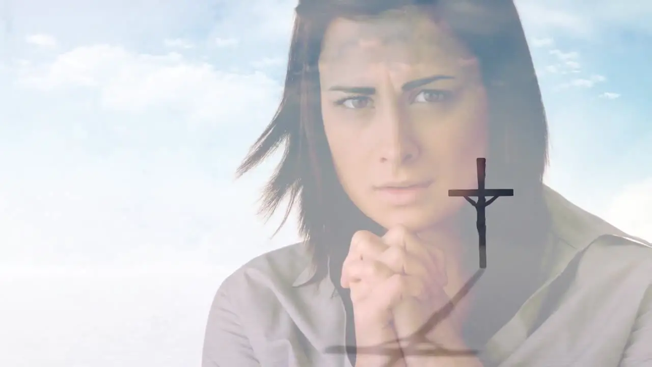 Video of crucifix over caucasian woman praying on cloudy sky