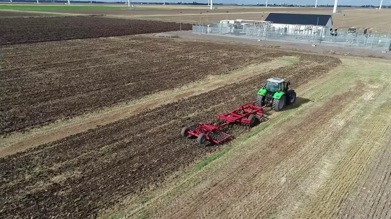 An aerial view from the drone as it circles a tractor tilling the land following the harvest and prepares it for the next crop