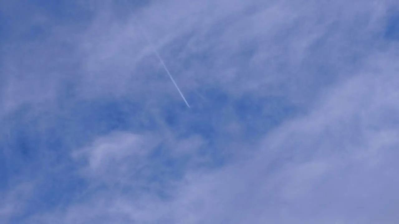 Contrails and vapor trail lines from an aeroplane aircraft flying overhead against a fine blue slightly cloudy sky