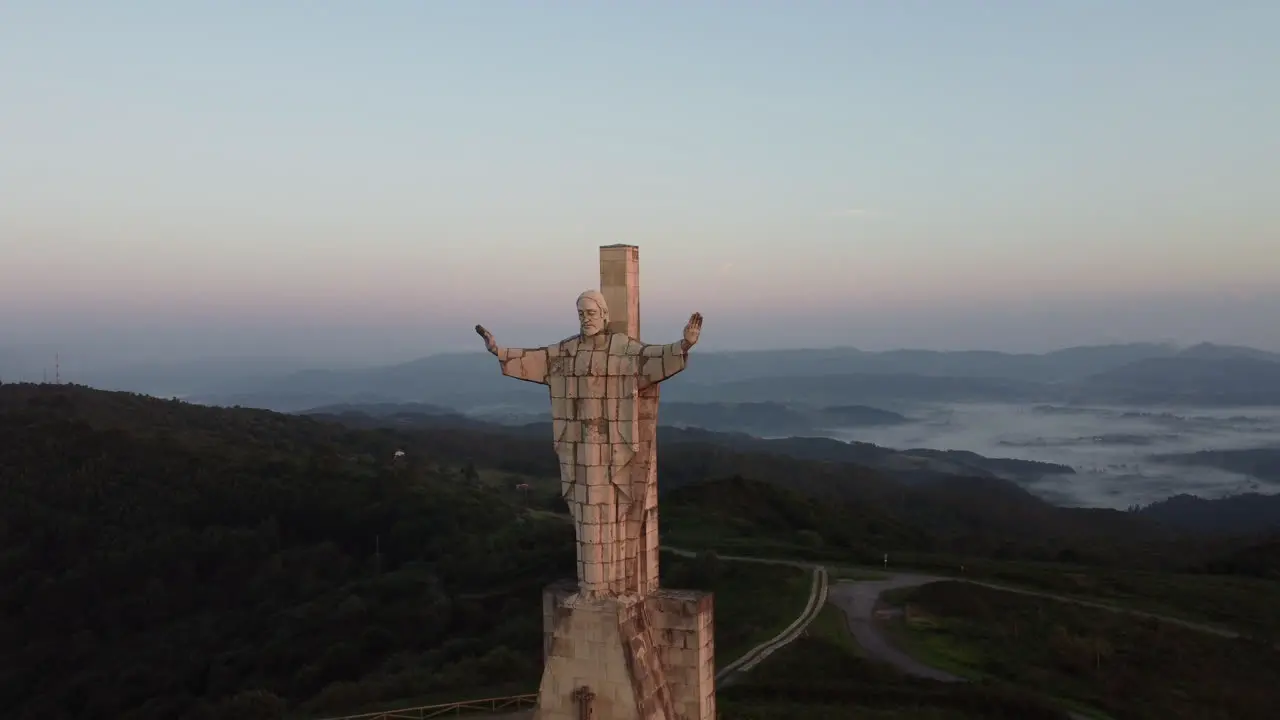 Reveal of a huge concrete statue at the top of a mountain