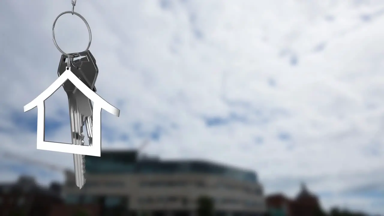 Animation of silver house model and key over defocused building against cloudy sky