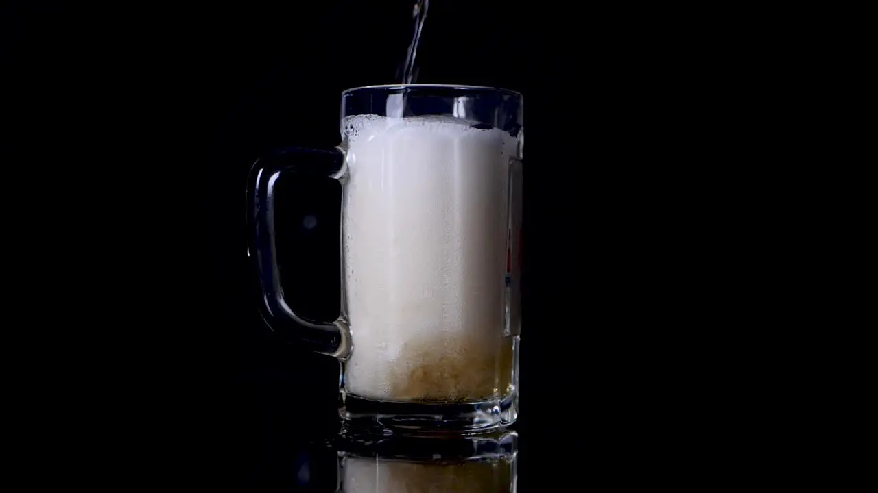 Slow motion shot of pouring beer in a mug until it spills over