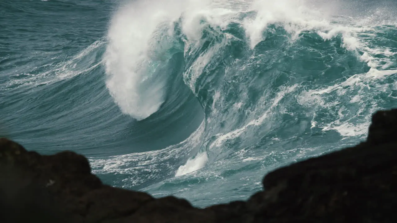 Foamy wave breaks in glass like slow motion behind the rock shelf