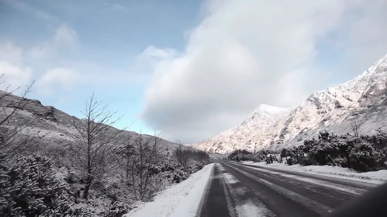 Road trip in the highlands Scotland snowy road white mountains at the background traveling shot