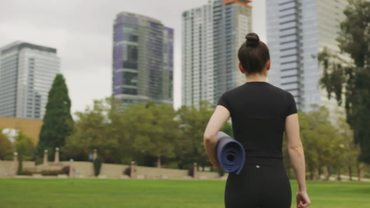 Rear view of a Caucasian woman walking to find a place to practice Yoga in a Seattle park