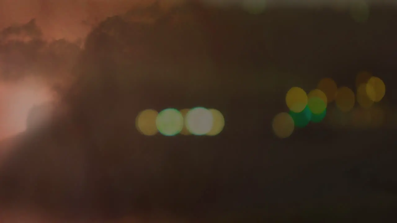 Transmission tower with bokeh lights and lightning in clouds