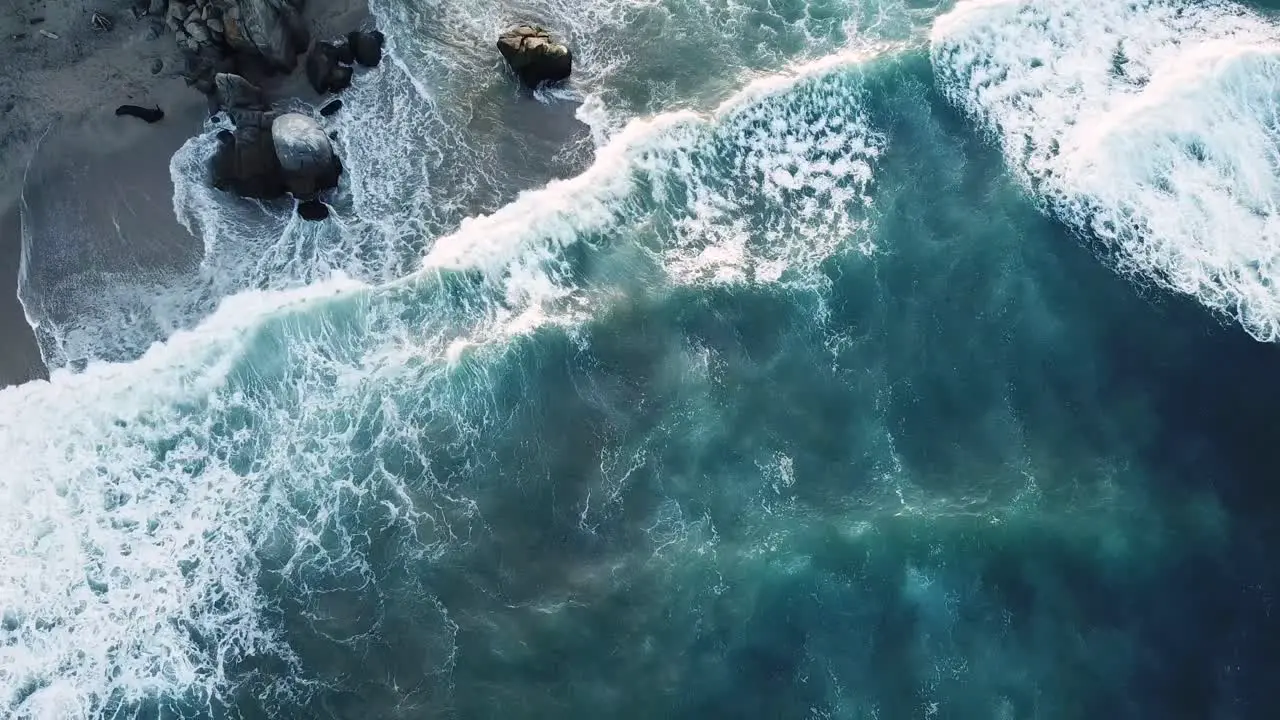 the blue and translucent waves smashing into the rocks on a windy day