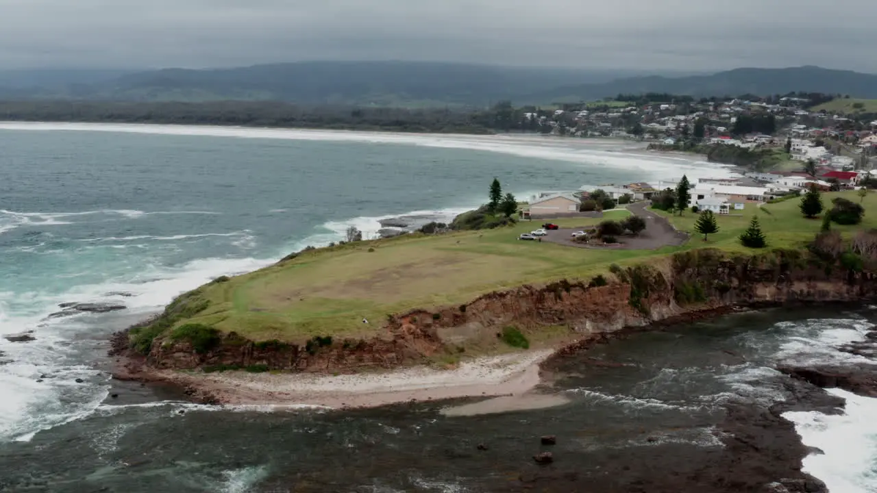 Aerial drone shot tracking left around Gerroa headland to reveal more of the town on stormy day in south coast NSW Australia