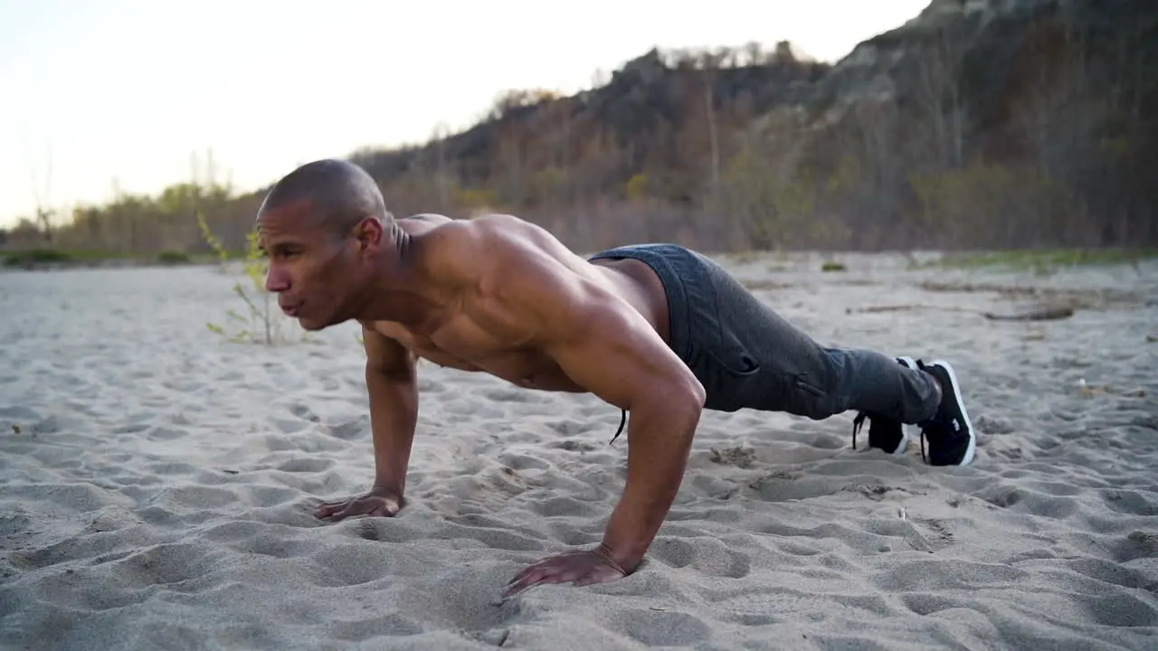 Attractive and athletic man doing push-ups on a beach