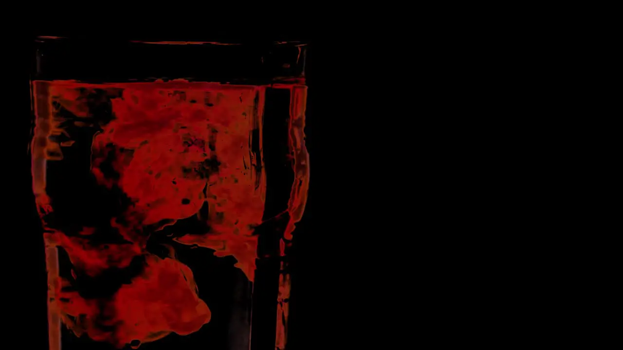 Red drops in water glass with black background