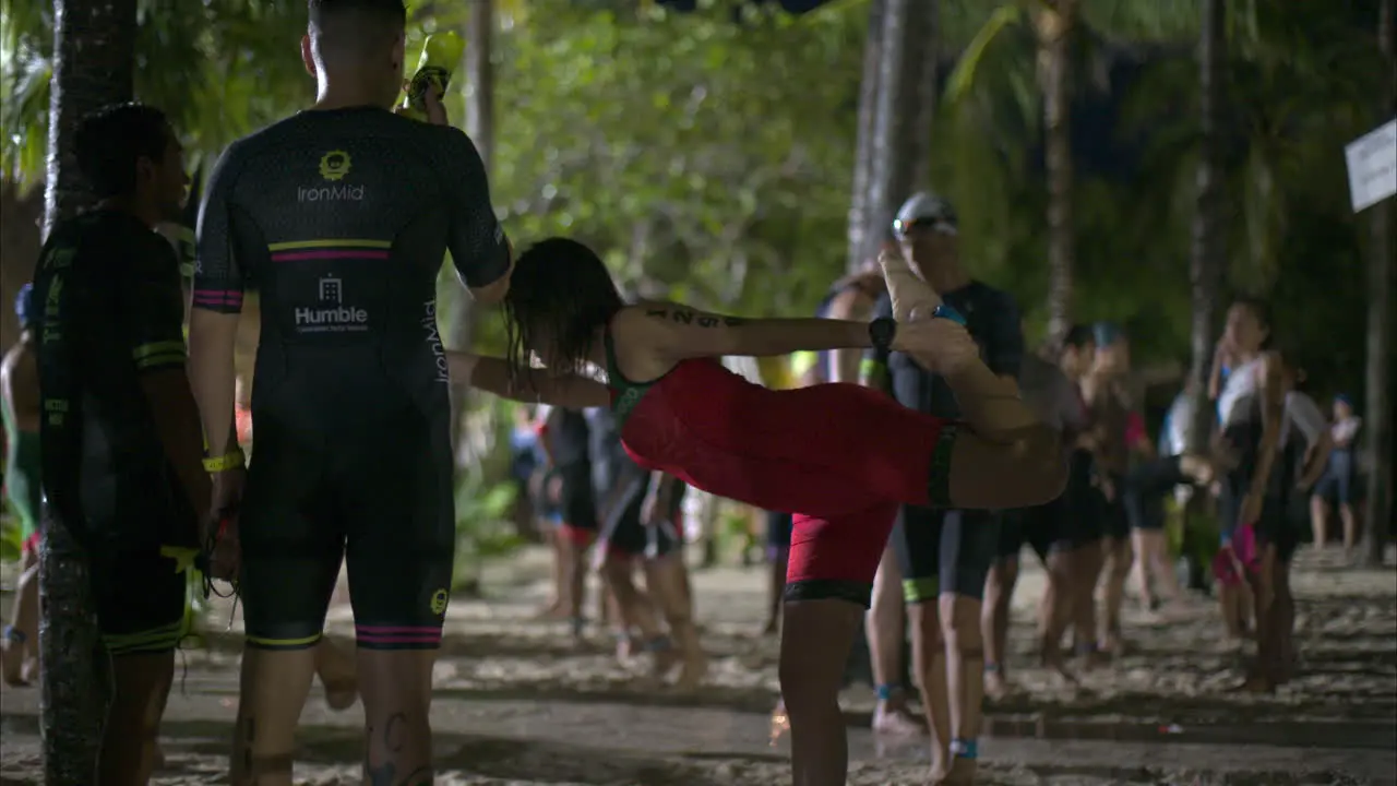 Male and female athletes wearing swimwear warming stretching and preparing for the start of the swimming stage of a triathlon on the beach