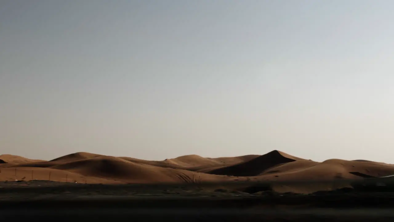 Driving through a middle eastern desert road with distant sand dunes and desert landscape in United Arab Emirates near Dubai