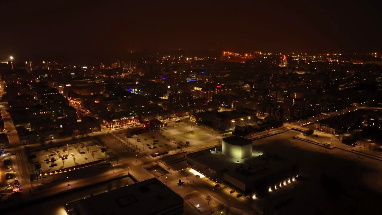 Aerial tracking shot of the illuminated market square and downtown Oulu misty winter evening in Finland