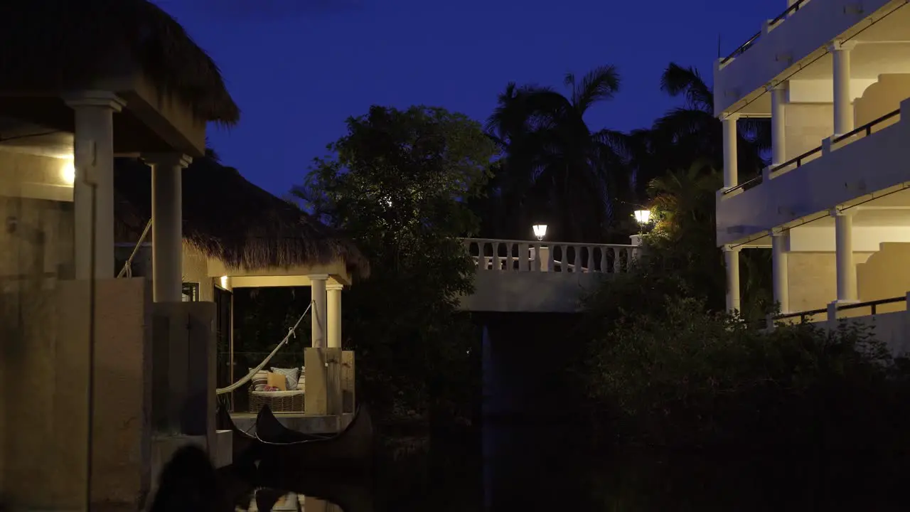 Stunning tranquil night time scene of small tropical bungalow's along a small river with a illuminated bridge above in a beautiful exotic vacation resort in Riviera Maya Mexico near Cancun and Tulum