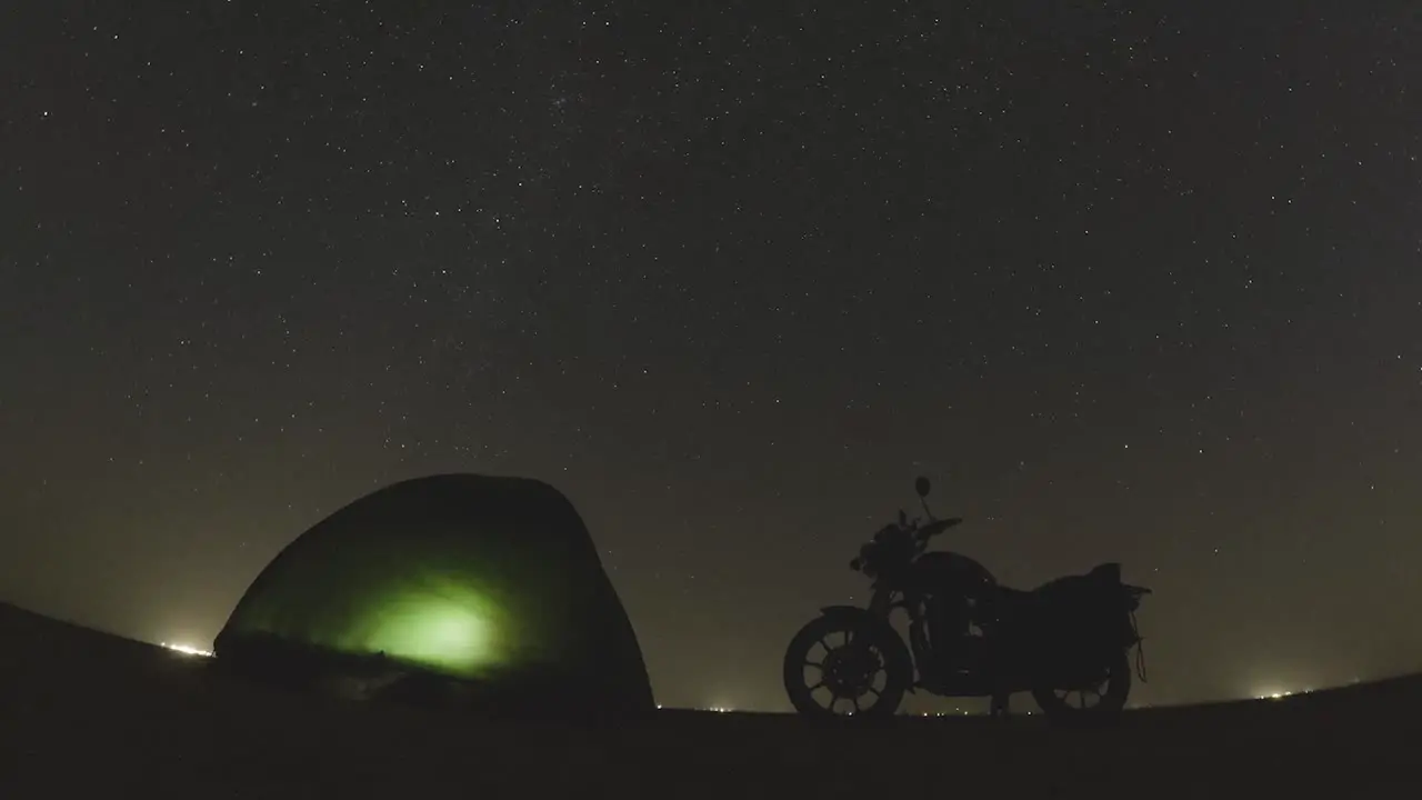 Timelapse of Stars in Night sky with tent camping and bike in foreground in a desert at Sambhar Lake Jaipur Rajasthan India