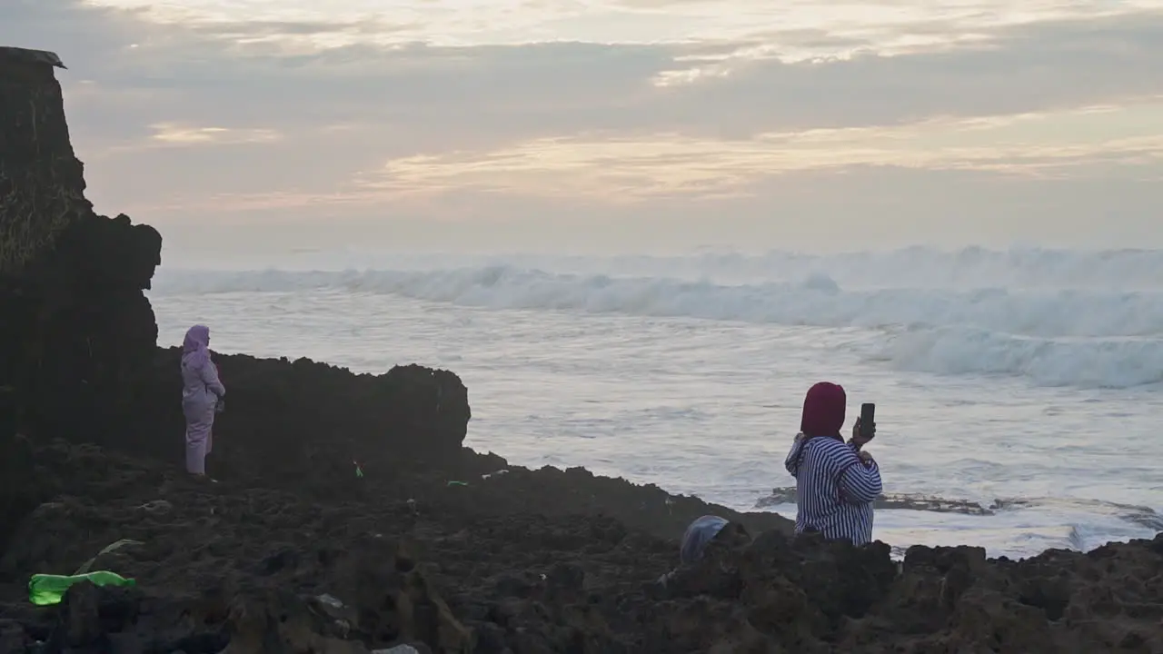 Muslim women watching the waves at sunset in Casablanca Morocco