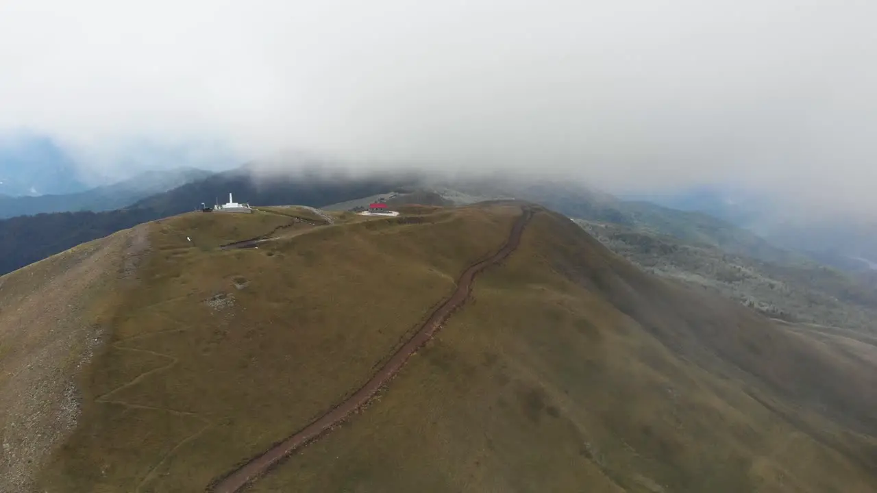 Drone video over foggy mountain monument Gramos dirt gravel roads Gkesos peak