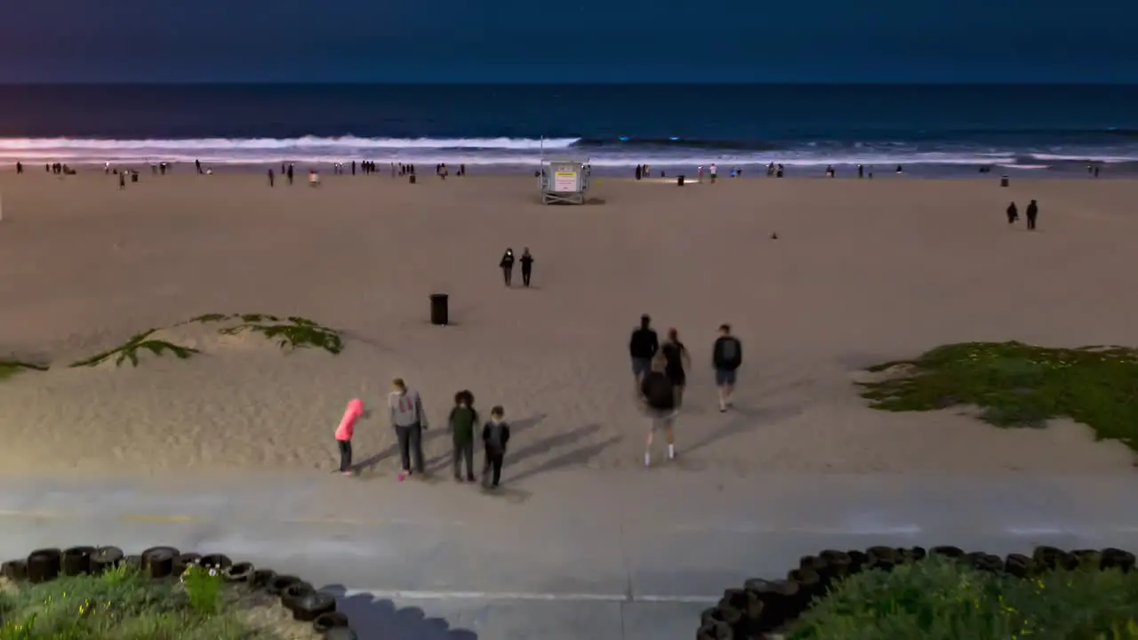 People Walking At The Strand Of Beach At Night With Wavy Ocean