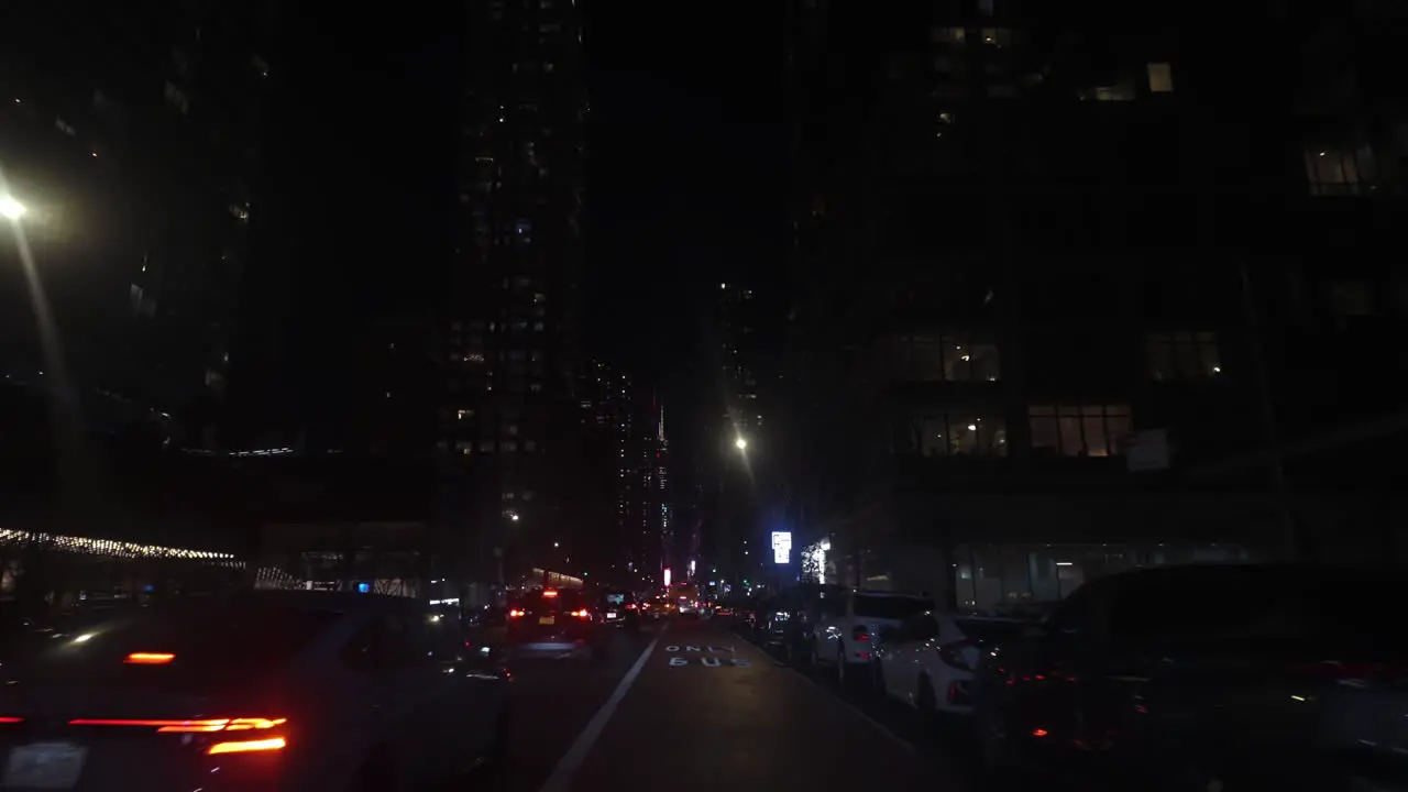 POV driving shot between illuminated skyscrapers of Manhattan nighttime in NYC