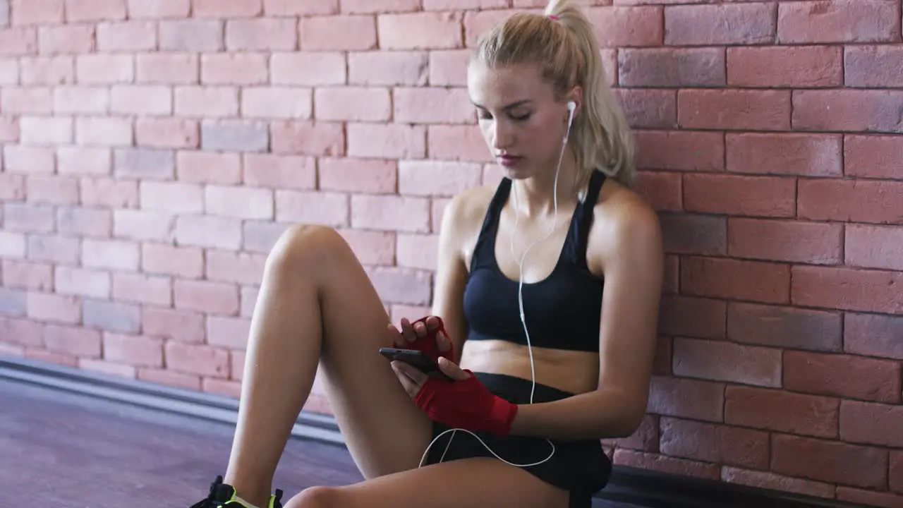 Sportswoman listening to music near wall